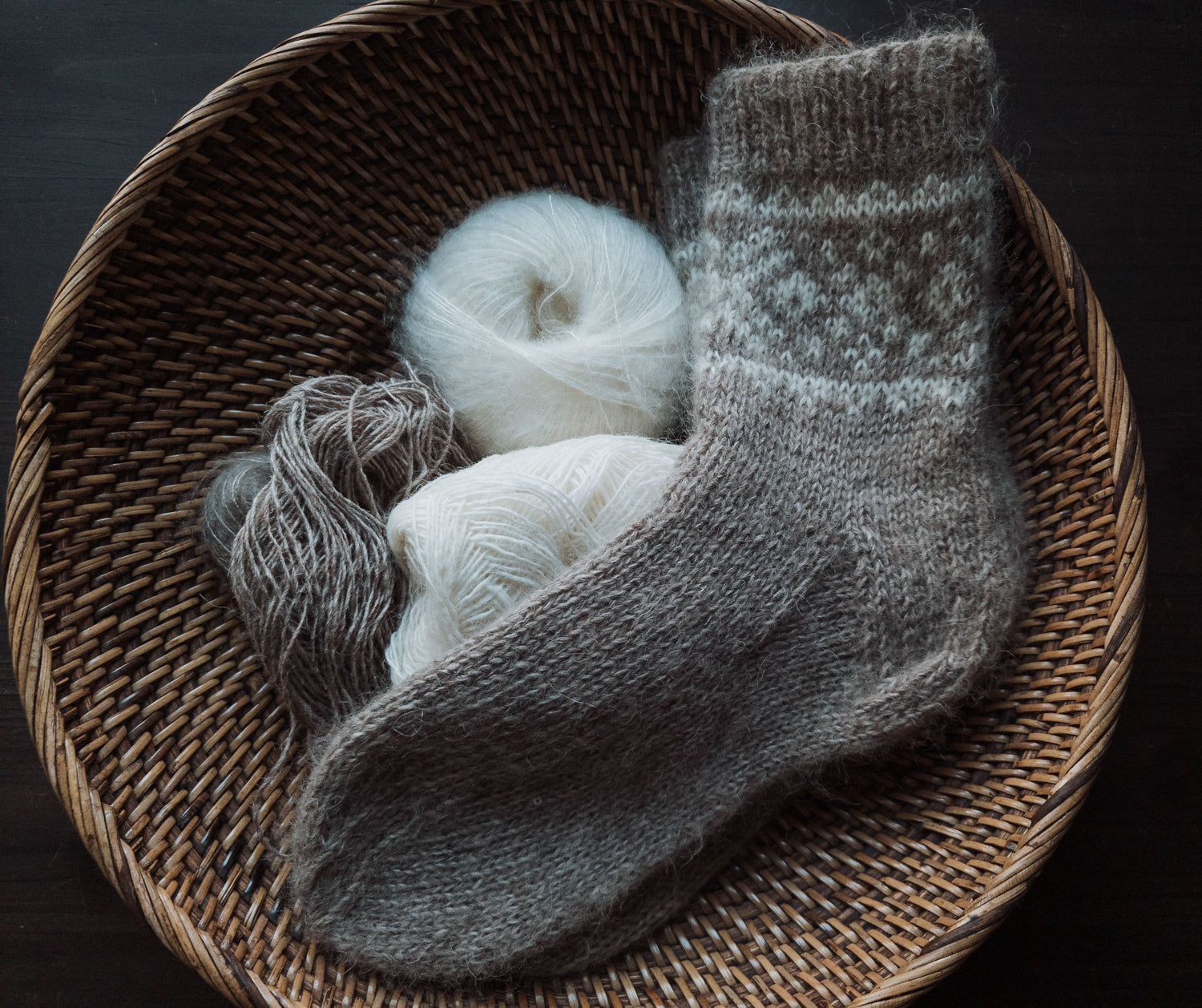 Hand-knit Arctic Sun socks and yarn in a woven basket.