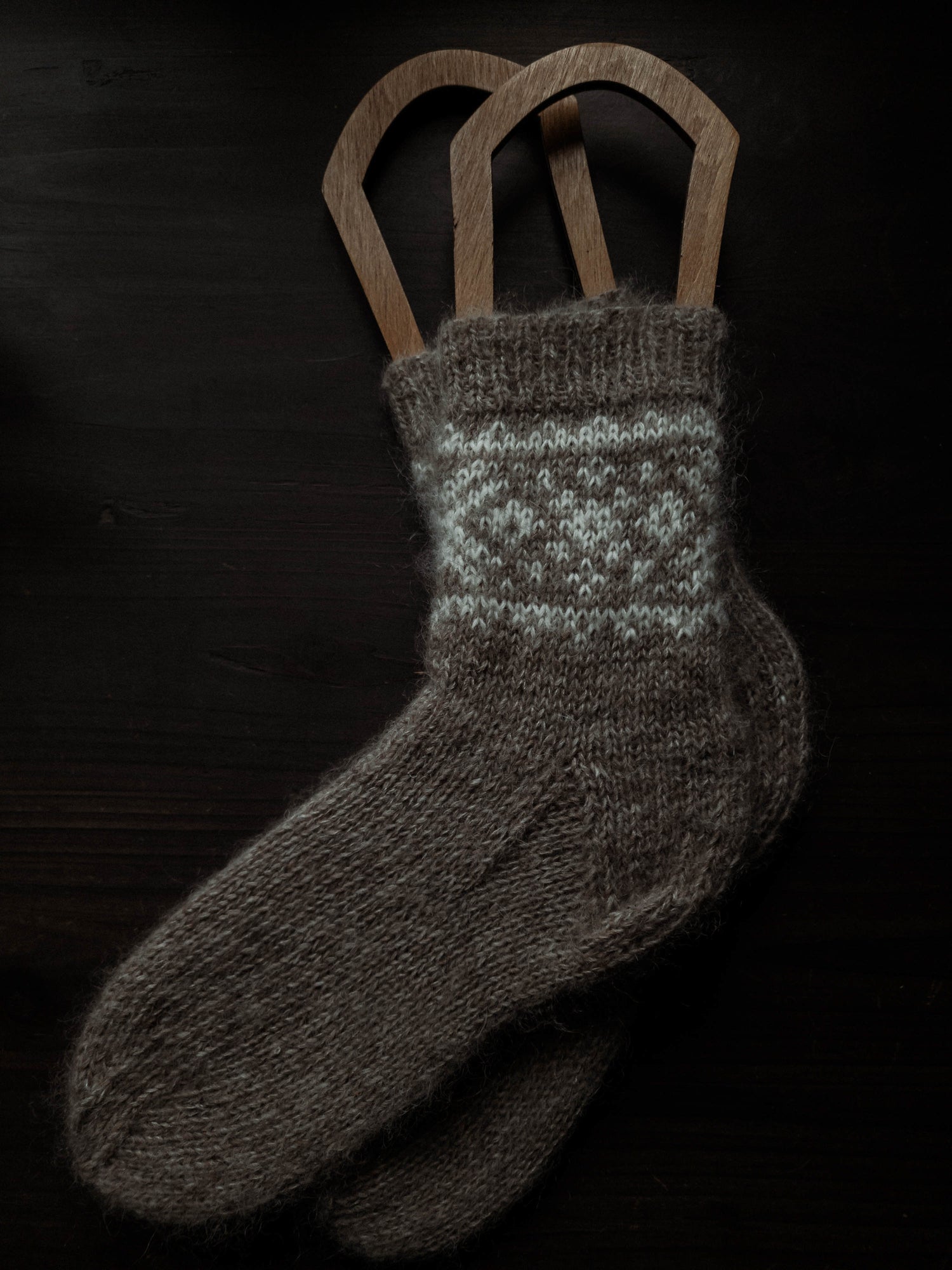 Hand-knit beige socks, colourwork, wooden blockers, textured heel.