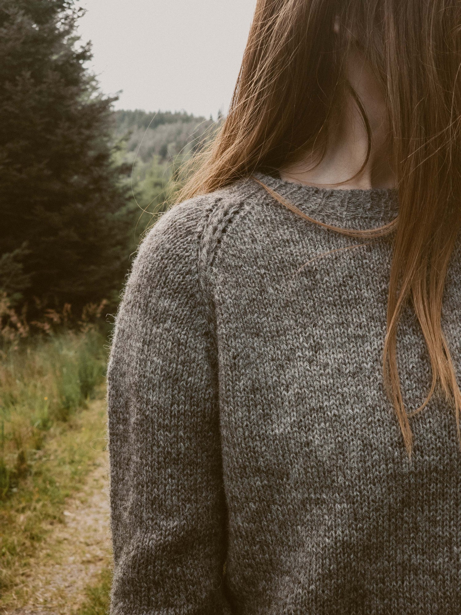 Close-up shot of the Wullpullover sweater handknit in Pommernglück from Calling Sheep, highlighting the front and shoulder detail with an intricate crochet braid.