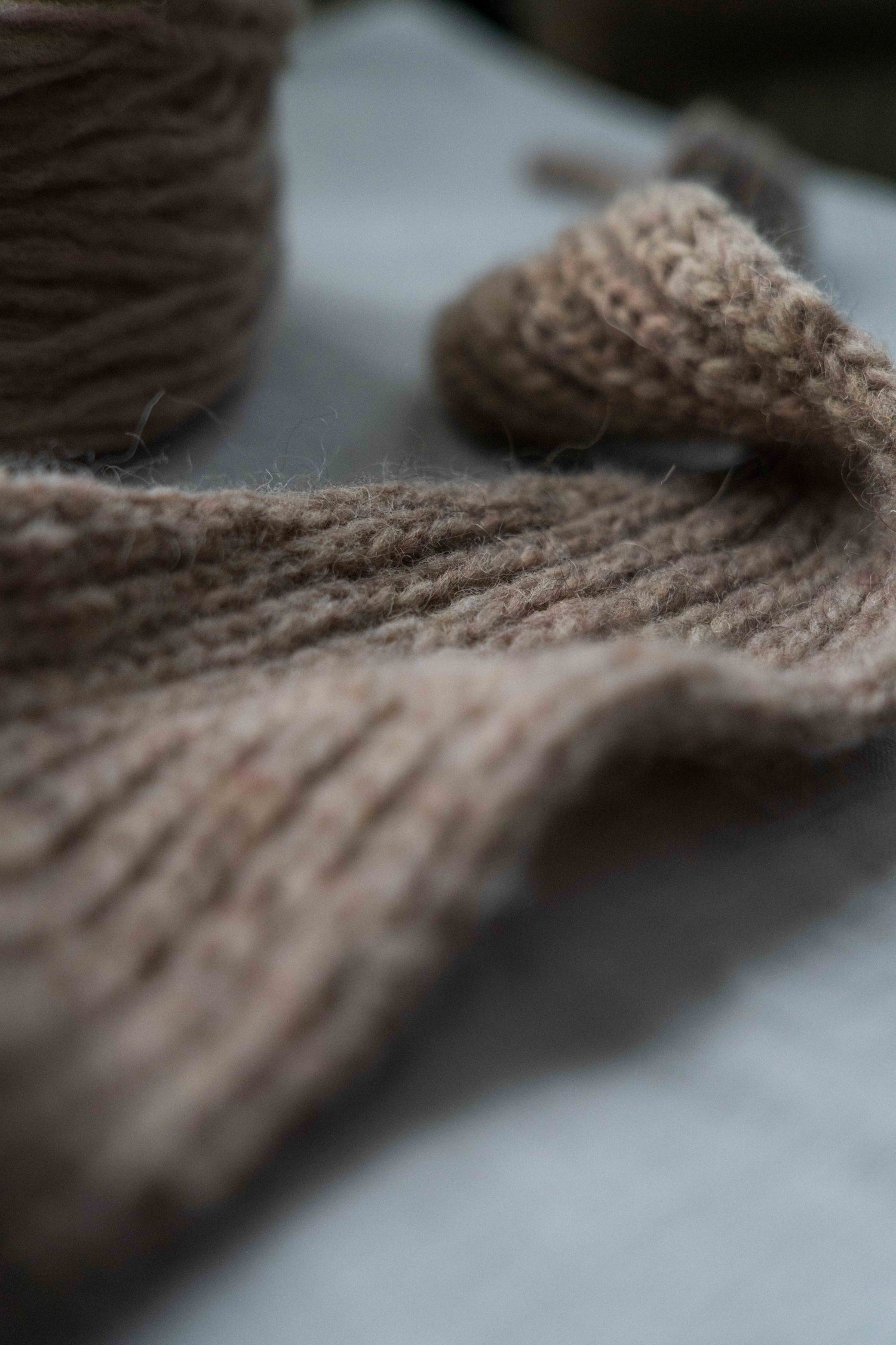 Close-up of the beige-pink Season's End Shawl, showcasing the half-brioche stitch and I-cord edges, handknit with Höner och Eir's unspun Nutiden yarn, laid on light grey linen.